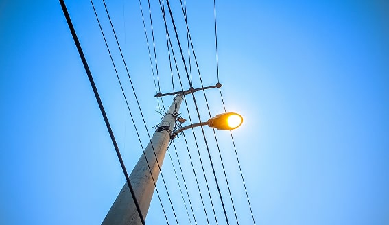 Utility pole with wires and lit streetlight.
