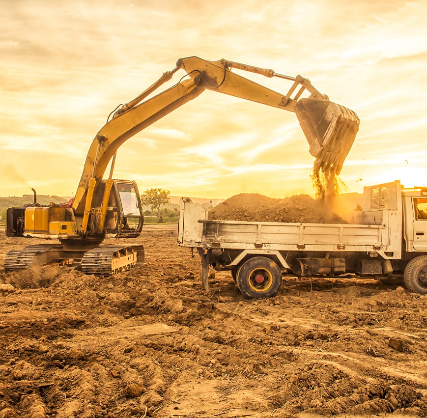 Yellow excavator loading dirt into a white dump truck.